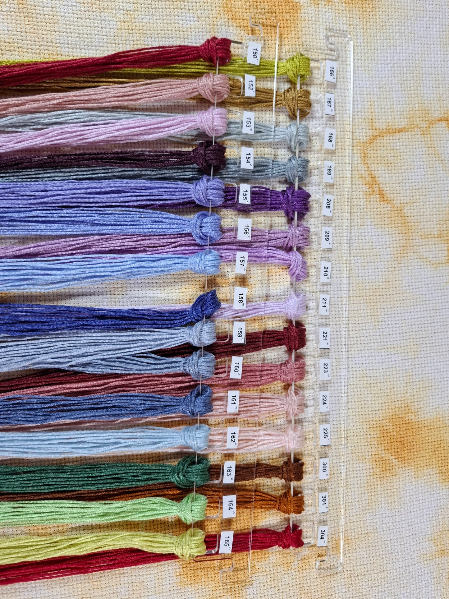 Organizador de hilos transparente con 15 colores de hilos ordenados y etiquetados.