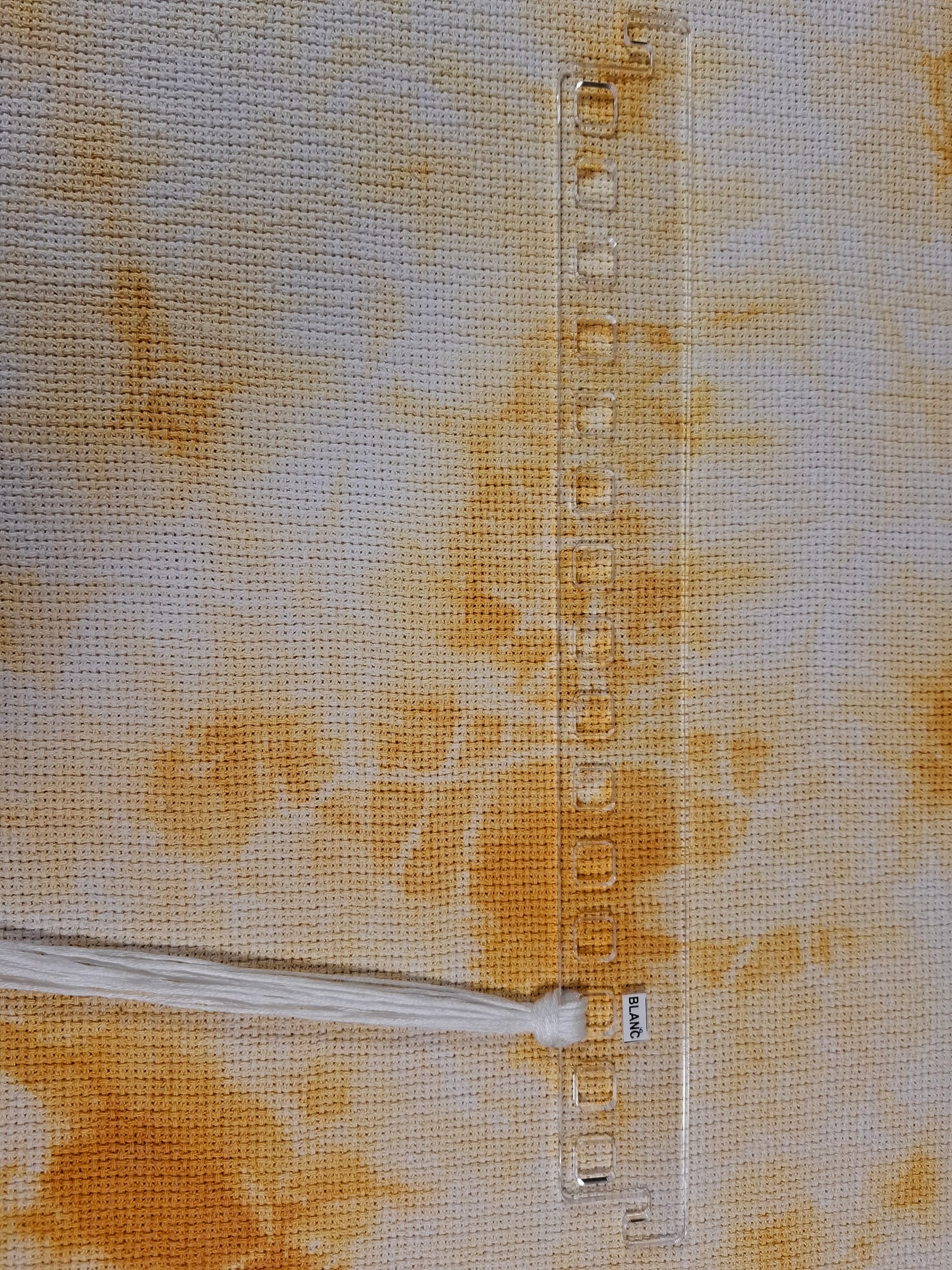 Colgador de hilos acrílico transparente sobre fondo texturizado, mostrando espacio para organizar 15 colores de hilos.